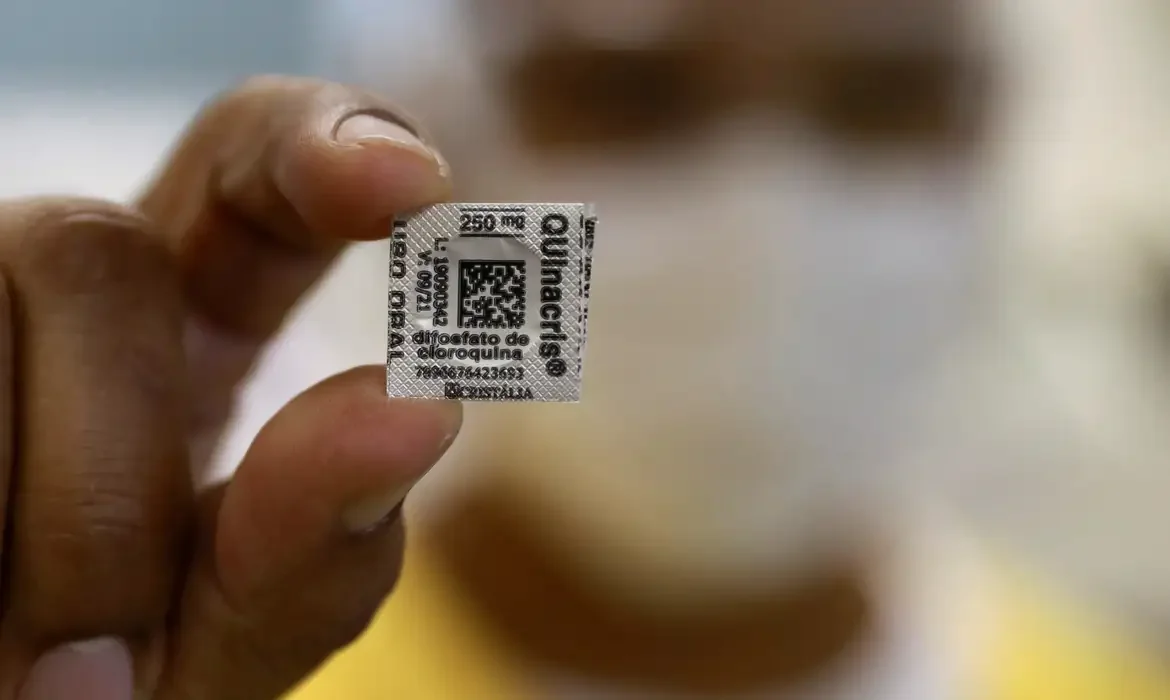 Pessoa segurando comprimido com QR Code na embalagem, destacando a necessidade de verificar a origem das informações.