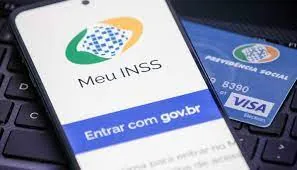 Aplicativo Meu INSS aberto em celular ao lado de cartão da Previdência Social