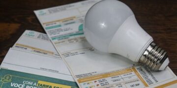 Conta de luz com lâmpada sobre mesa de madeira indicando custos de energia