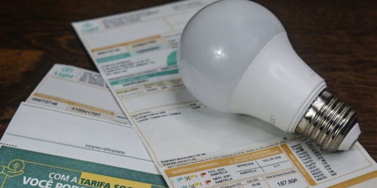 Conta de luz com lâmpada sobre mesa de madeira indicando custos de energia