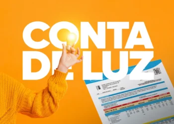 Pessoa segurando uma lâmpada acesa ao lado de uma conta de luz, destacando a possibilidade de isenção para quem está no CadÚnico e ganha até meio salário mínimo.
