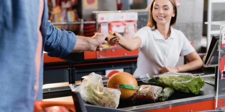 Pessoa usando cartão de vale-alimentação no caixa de supermercado