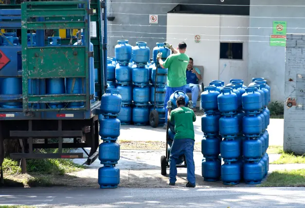 Trabalhadores descarregam botijões de gás em centro de distribuição, relacionados ao programa Auxílio Gás.