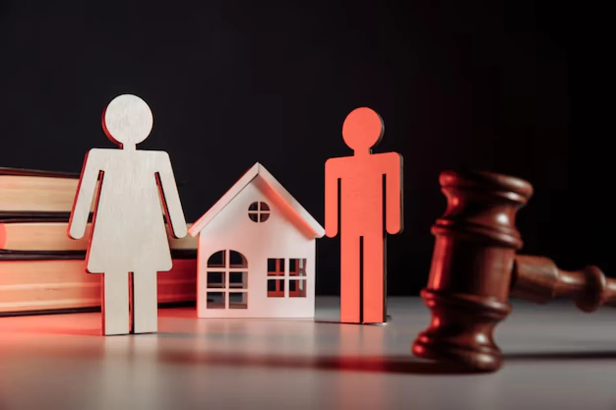 Divisão de bens após o divórcio representada por figuras de homem e mulher com casa e martelo de juiz ao fundo
