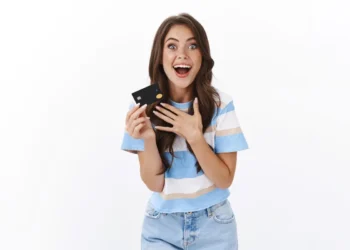 Jovem feliz segurando um cartão de crédito preto, simbolizando economia com cashback em 2025.