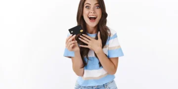 Jovem feliz segurando um cartão de crédito preto, simbolizando economia com cashback em 2025.