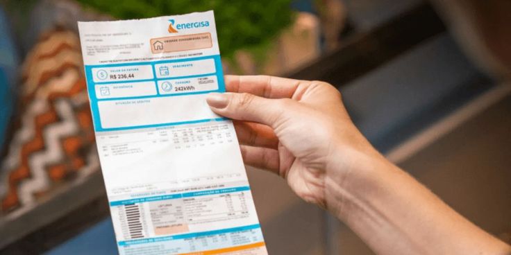Mão segurando uma conta de energia elétrica da Energisa