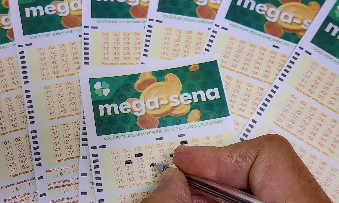 Pessoa preenchendo manualmente um volante de apostas da Mega-Sena.