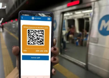 Pessoa segura celular com bilhete digital contendo QR Code em estação de metrô.