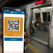 Pessoa segura celular com bilhete digital contendo QR Code em estação de metrô.