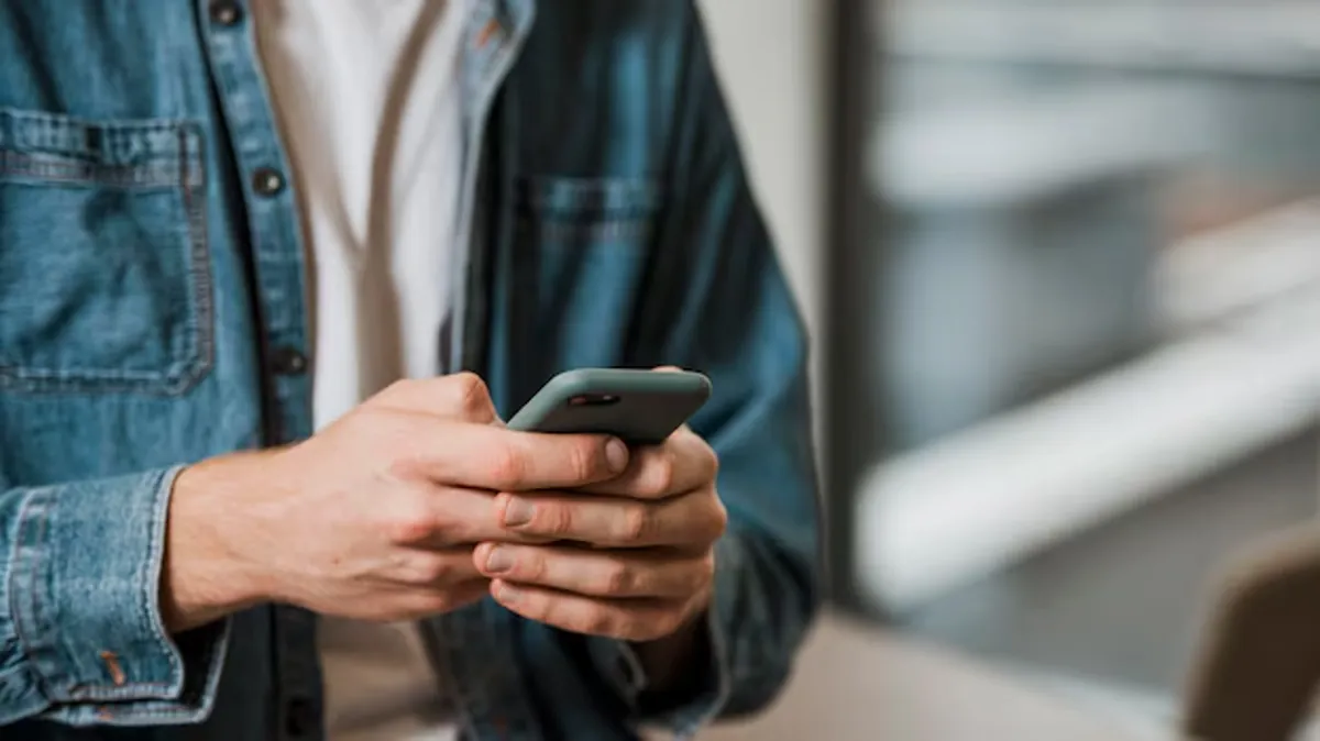 Pessoa segurando celular, representando atenção ao uso de aplicativos e segurança digital