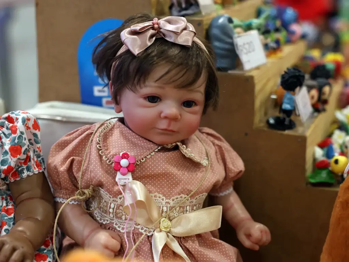 Boneca bebê reborn vestida com vestido rosa, com expressão realista.