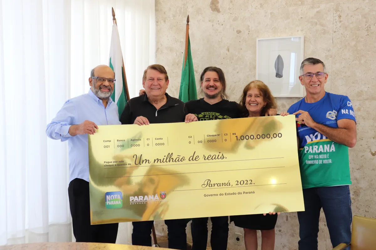 Grupo de pessoas segurando cheque simbólico de um milhão de reais do Governo do Paraná, destacando o programa Nota Paraná e o prêmio CPF Premiado."