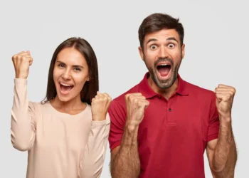 Casal comemorando vitória com expressões de felicidade e braços erguidos.