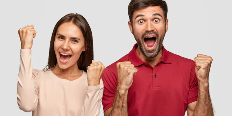 Casal comemorando vitória com expressões de felicidade e braços erguidos.