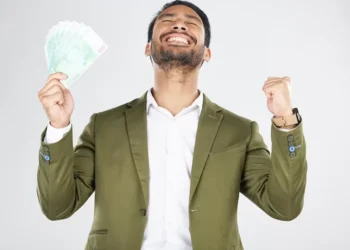 Homem feliz segurando dinheiro em notas verdes, comemorando vitória.