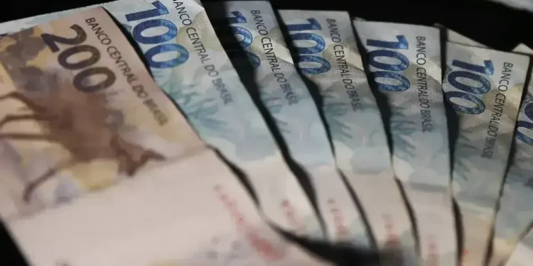 Notas de R$ 100 e R$ 200 dispostas de forma visível, representando o pagamento de R$ 2.424.