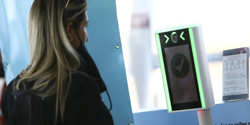 Mulher utilizando um sistema de biometria facial em um processo de verificação de segurança.