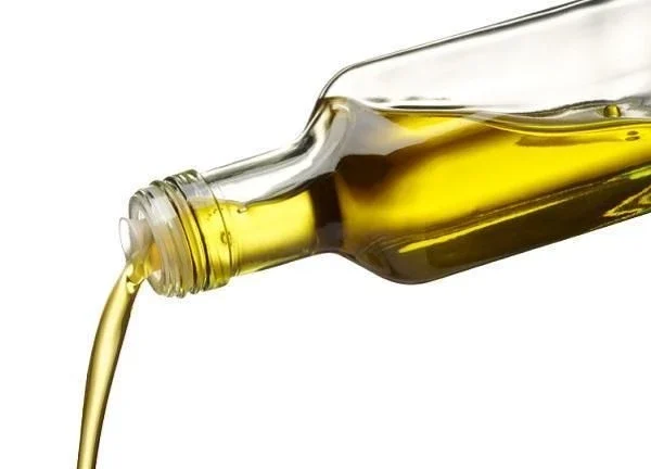 Fluxo de azeite dourado sendo despejado de uma garrafa transparente.