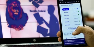 "Pessoa acessando a consulta de declarações do IRPF pelo celular, com logo da Receita Federal ao fundo."