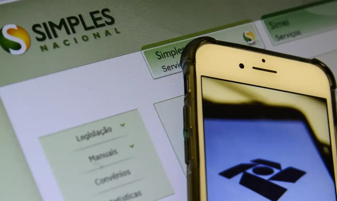 Imagem mostrando a tela do sistema Simples Nacional e a logo do MEI em um smartphone, ilustrando a declaração anual do MEI.