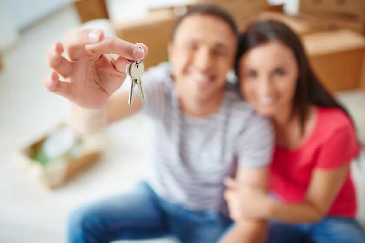  Chaves de imóvel nas mãos de casal feliz, simbolizando oportunidade em leilão de imóveis com descontos.