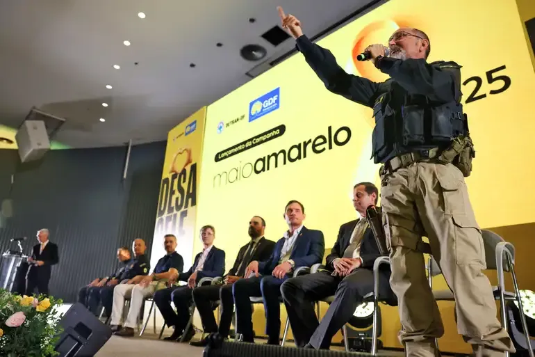 "Lançamento da campanha Maio Amarelo, com representantes e um policial em evento sobre segurança no trânsito."
