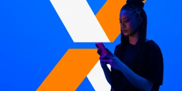 Mulher usando smartphone com logo da Caixa ao fundo, representando o internet banking da Caixa.