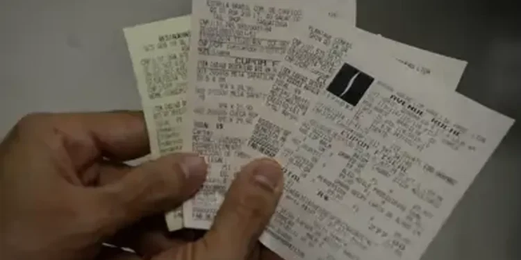 Pessoa segurando várias notas fiscais em mãos.