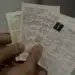 Pessoa segurando várias notas fiscais em mãos.
