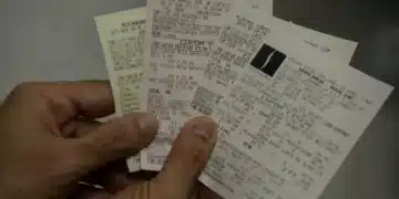 Pessoa segurando cupons fiscais, participando do sorteio 'Nota Premiada'