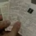 Pessoa segurando cupons fiscais, participando do sorteio 'Nota Premiada'