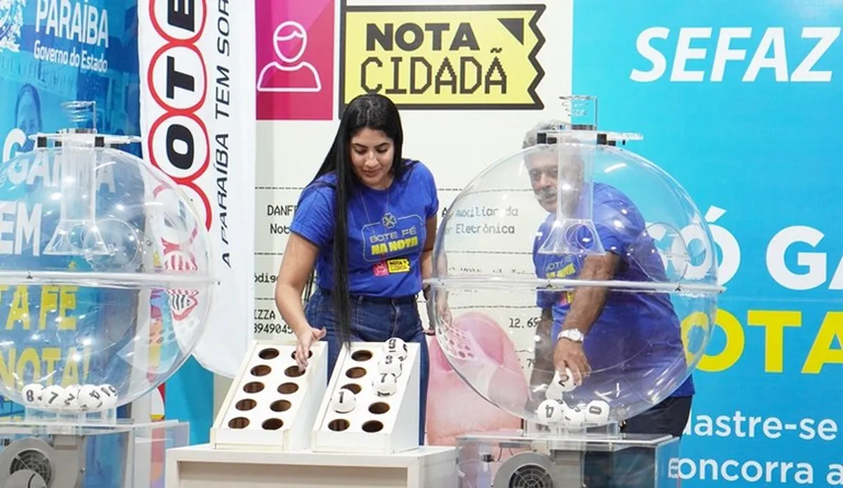 Pessoas realizando o sorteio do programa Nota Cidadã com bolas numeradas e urnas transparentes.