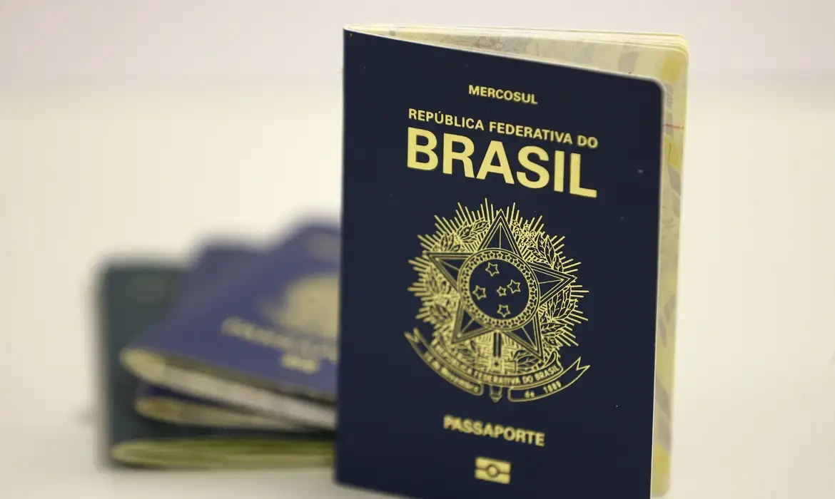 Passaporte brasileiro aberto destacando a capa azul com o brasão do Brasil.