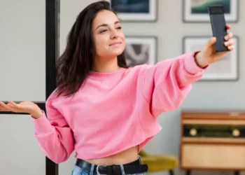 Mulher tirando selfie com celular, fazendo expressão de dúvida