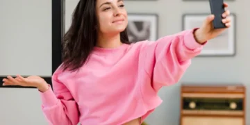 Mulher tirando selfie com celular, fazendo expressão de dúvida