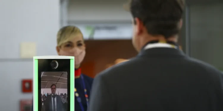 Imagem de uma mulher realizando biometria facial em um senhor