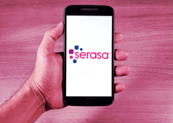 Imagem de uma mão segurando um smartphone com o logo da Serasa, mostrando a tela em um fundo roxo e elegante.