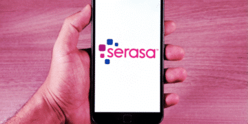 Imagem de uma mão segurando um smartphone com o logo da Serasa, mostrando a tela em um fundo roxo e elegante.