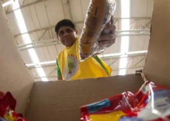 Voluntário entregando cesta básica em caixa de papelão.