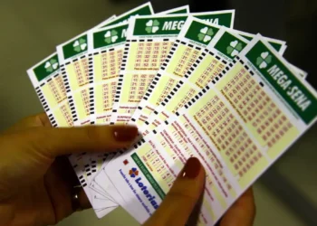 Pessoa segurando vários bilhetes de apostas da Mega-Sena.