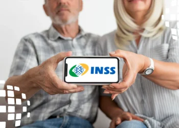 Casal de idosos segurando celular com logo do INSS, ilustrando consulta e pagamento de benefícios em maio de 2025.