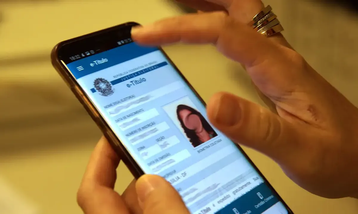 Pessoa verificando título de eleitor digital no celular, destacando a importância da regularização eleitoral.