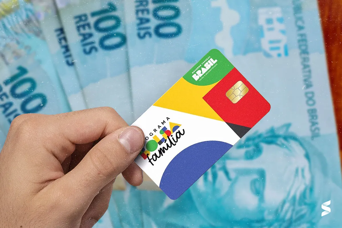 Pessoa segurando o novo cartão do Bolsa Família com cédulas de 100 reais ao fundo.