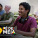 Estudante sorrindo enquanto usa um laptop em sala de aula, com outros alunos ao fundo, representando a temática do benefício educacional do Pé-de-Meia.