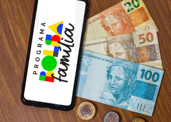 Dinheiro em notas e celular com o logo do Programa Bolsa Família.