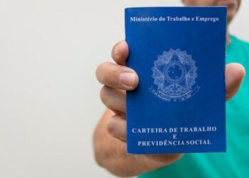 Carteira de Trabalho sendo exibida por trabalhador de camisa verde