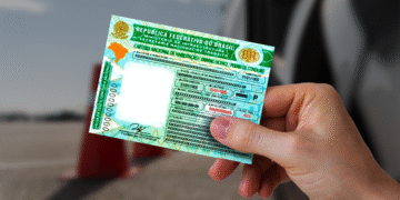 Carteira Nacional de Habilitação sendo segurada por uma pessoa, mostrando detalhes do documento oficial.