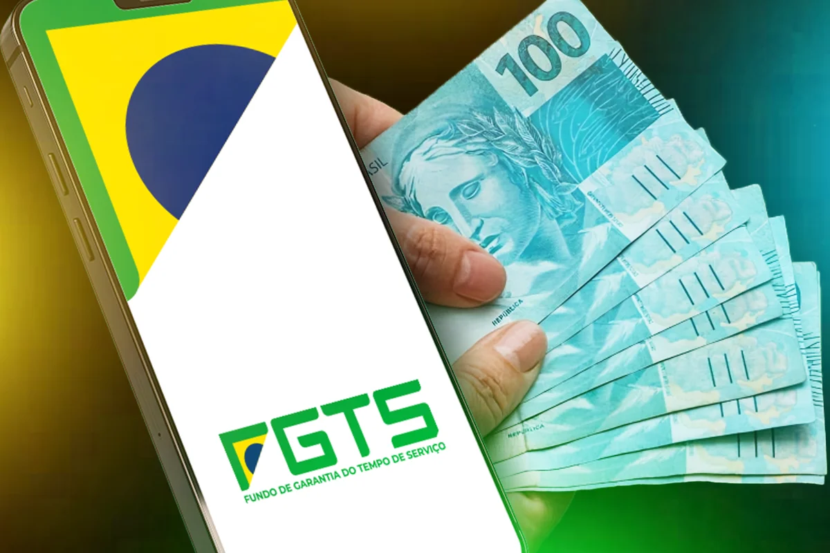 Imagem de um celular com a tela do aplicativo do FGTS e cédulas de R$ 100 sendo seguradas por uma mão, representando o saque-aniversário do FGTS