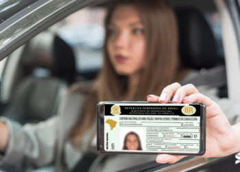 Imagem de uma pessoa mostrando sua CNH digital enquanto está dentro de um carro, com foco na tela do celular que exibe o documento.